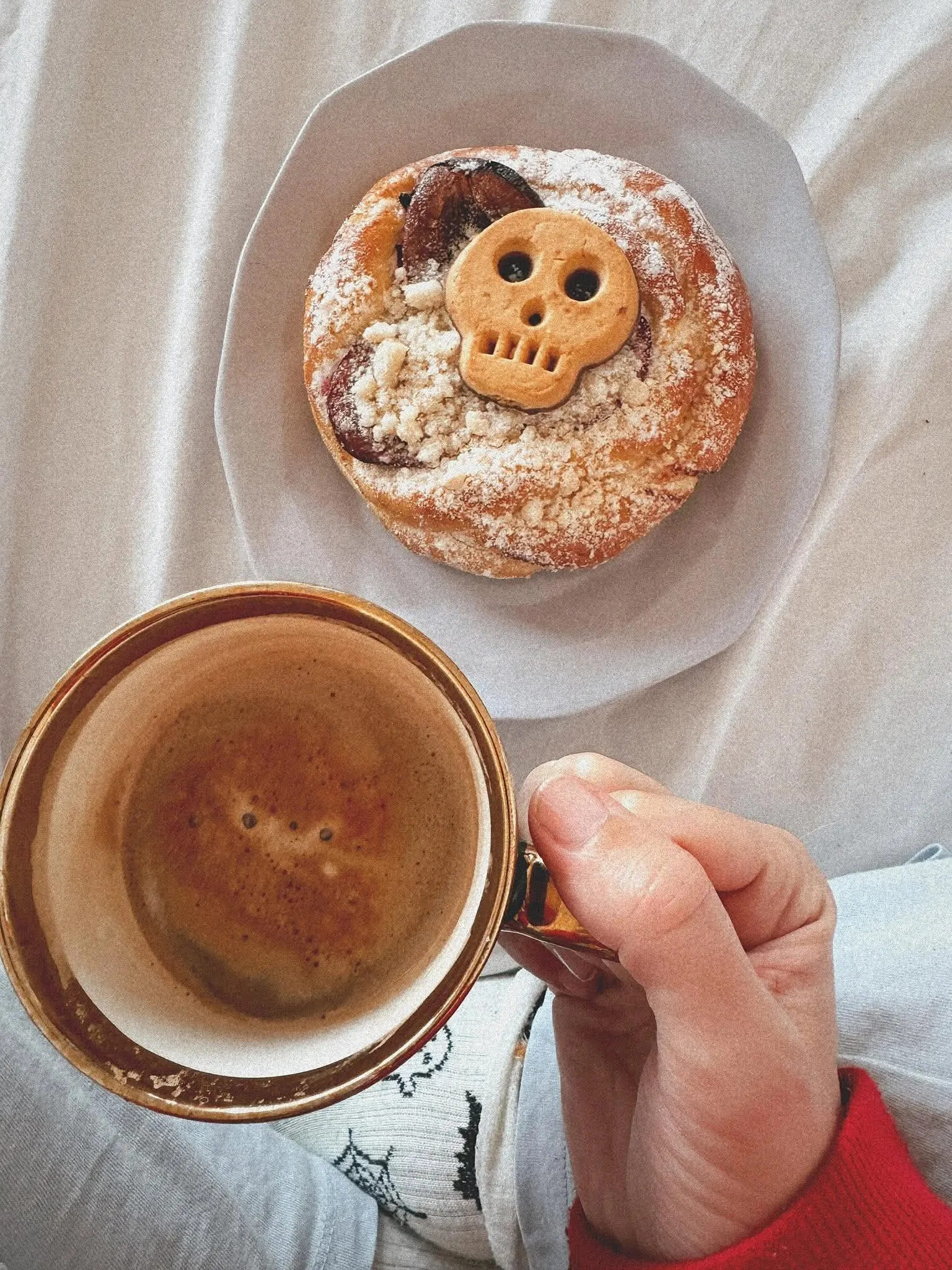 Plum bun with a skull cookie and a cup of coffee